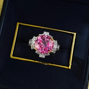 Macro detail of round pink sapphire ring with tapered baguette diamonds in jewelry box