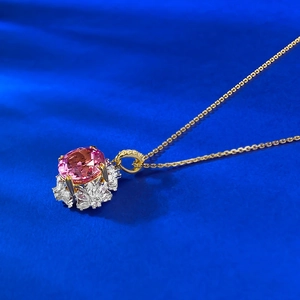 Macro detail of oval pink sapphire pendant with marquise diamond halo and gold chain