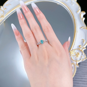Détail d'une bague avec pierre précieuse bleu clair ovale et accents de diamants