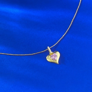 Collana in argento a forma di cuore rosa placcata oro su sfondo di seta blu scuro