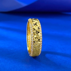 Macro shot of gold wide-band ring featuring central sequin texture and side zircon stones