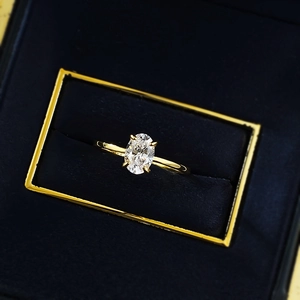 Macro close-up of an oval-cut solitaire ring set in a dark blue velvet jewelry box