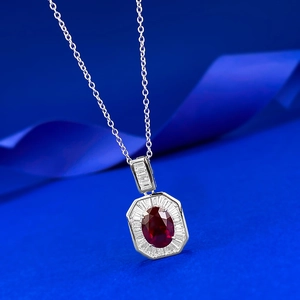 Gros plan d'un pendentif en rubis sang de pigeon avec zircons sur une fine chaîne en argent