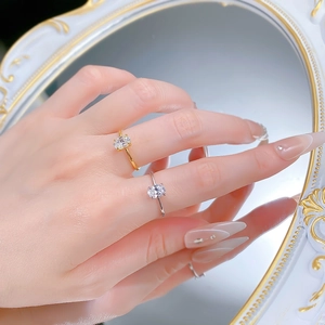 Detailed view of silver and gold oval cut solitaire rings worn on a hand with luxury mirror