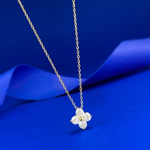 Macro detail of gold four-leaf clover pendant with sparkling gems on blue silk