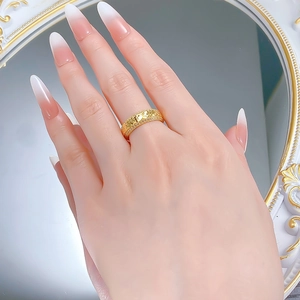 Close-up of a wide gold-plated silver ring with iced-out zircon and embossed texture