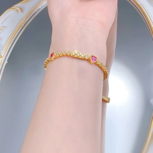 Detailed macro view of S925 silver gold-plated bracelet with pink heart-shaped gemstones