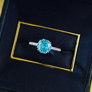 Macro shot of sky blue petal-cut gemstone and pave diamond silver ring in gift box