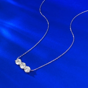 Collana in argento S925 con tre pietre preziose rotonde su uno sfondo blu intenso