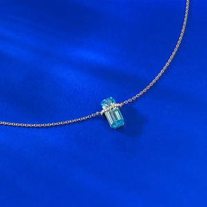 Macro shot of rectangular blue topaz pendant with diamond accents on a rose gold chain