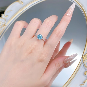 Macro view of blue floral-cut gemstone ring on hand with silver diamond-set band