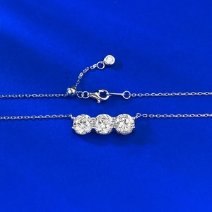 Collana in argento S925 con ciondolo a tre pietre su sfondo di tessuto blu scuro