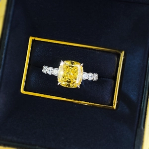 Macro shot of cushion cut yellow gemstone ring set in silver in a blue jewelry box