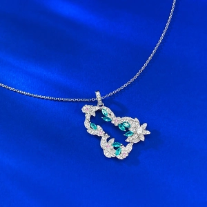 Macro della collana in argento S925 con pietre verdi su un panno di seta blu reale
