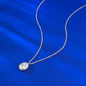 Détail d'un pendentif avec pierre ovale sertie en argent sur un tissu en soie bleu foncé