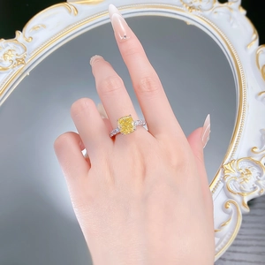 Close-up of yellow cushion cut gemstone ring on model finger against a white mirror