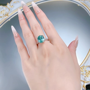 Détail d'une bague avec pierre précieuse ovale bleu-vert et pavage diamants sur argent