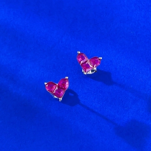 Mini S925 sterling silver heart studs with ruby-colored gems on a textured blue background