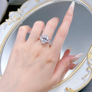 Three-stone ring with oval clear gemstone and pear-cut side stones worn on hand