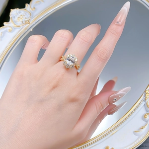 Detailed close-up of a twisted gold ring with a large rectangular gemstone worn on a finger