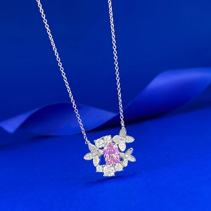 Dettaglio macro di collana in argento con farfalla e gemma rosa su seta blu lussuosa