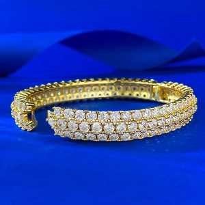 Close-up of a three-row pave-set diamond gold bracelet on a deep blue satin background