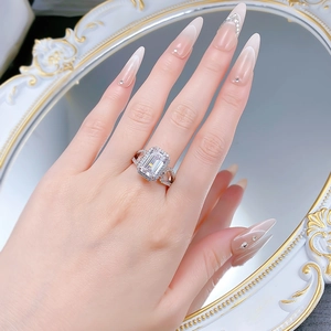 Detailaufnahme von Ring mit Smaragdschliff-Diamant und Halo-Fassung auf Pavé-Ringschiene
