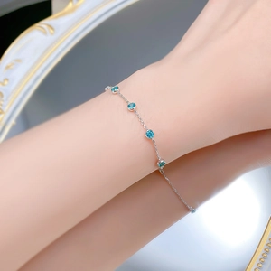 Detail of silver S925 bracelet with blue paraiba gems worn on wrist near a vintage mirror