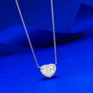 Macro shot of S925 silver heart-shaped pendant with halo stones on a blue background