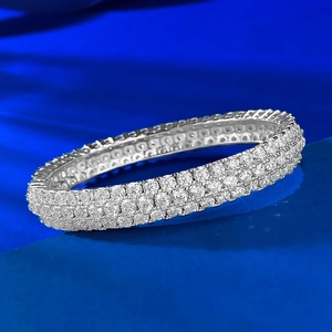 Macro shot of silver finish three-row pave-set cubic zirconia band on navy background