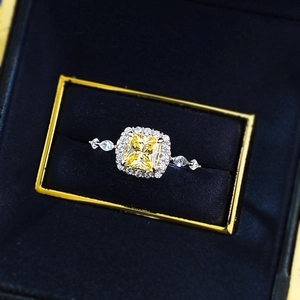 Macro shot of princess cut yellow gemstone ring with side stones in luxury gift box