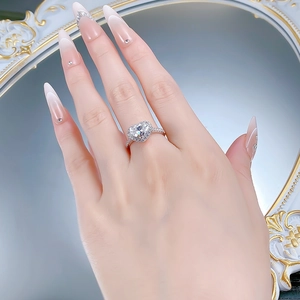 Gros plan d'une bague coeur en argent sertie de diamants sur une main aux ongles longs