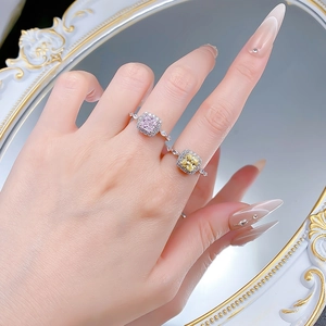 Detailed view of pink and yellow princess cut halo rings on finger with a vintage mirror