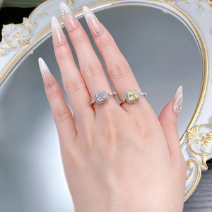Detail of S925 silver rings with yellow and pink princess-cut stones on a finger