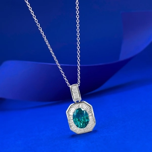 Gros plan du pendentif argenté octogonal avec pierre verte et diamants de taille baguette