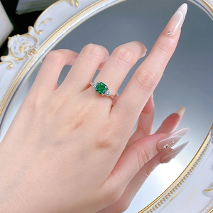 Detailed view of an S925 silver ring featuring a 2ct emerald cut green stone on a finger