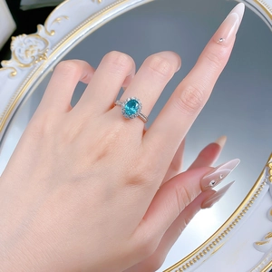 Close-up of S925 silver ring with oval cut paraiba color stone and halo diamonds on hand