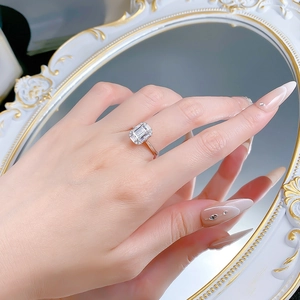 Dettaglio di un anello in argento taglio smeraldo con alone indossato da una modella