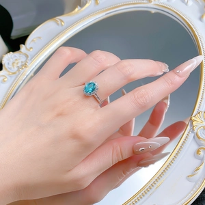 Close-up of S925 silver ring with 1.5ct oval blue stone worn by a female model