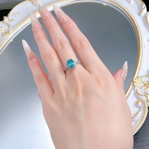 Detailed view of oval Paraiba color gemstone ring with halo diamonds on a textured band