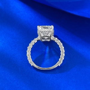 Macro view of emerald-cut gemstone ring with side diamonds on blue silk background
