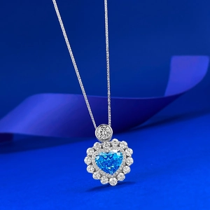 Close-up of S925 silver heart necklace with blue gem and halo diamonds on blue ribbon
