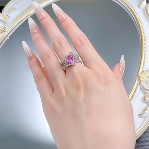 Detailed close-up of a pink oval gemstone ring with lace silver setting on a hand