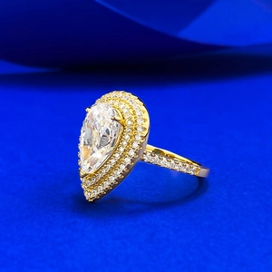 Macro shot of gold pear-cut ring with double halo pavé setting on blue background