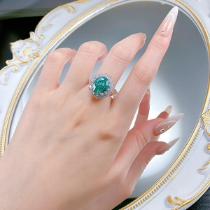 Macro detail of S925 silver ring featuring a large green gemstone with double halo diamonds