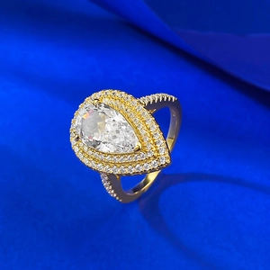 Macro view of gold pear-cut diamond ring featuring a luxury double halo on blue silk
