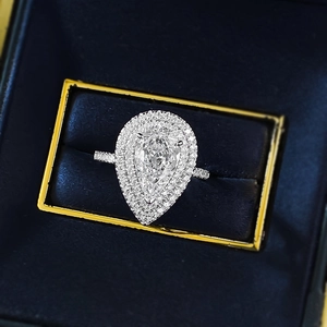 Macro view of pear-cut sparkling diamond ring with double halo in blue velvet box