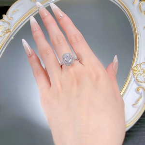 Close-up of an oval halo ring with double row of pavé diamonds on a hand