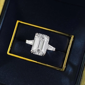 Emerald cut solitaire ring with tapered baguette stones in a premium blue velvet jewelry box