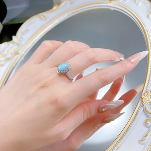 Gros plan d'une bague en argent S925 avec larimar bleu et halo de zircons au doigt